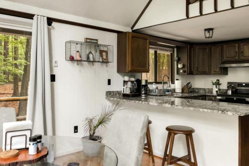 a kitchen with a counter and a table and chairs at Enchanting A-Frame Cabin Retreat near Berkeley Springs and Mountain Views in West Virginia in Baxter