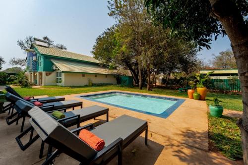 a swimming pool with lounge chairs next to a house at Kasongo Lodge in Victoria Falls