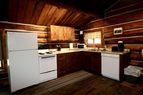 a kitchen with a white refrigerator and wooden cabinets at Unique Camping Cabin Tucked in Wilderness near Steamboat Springs, Colorado in Columbine