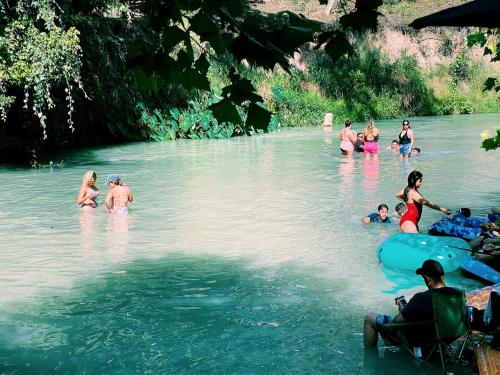 a group of people swimming in a river at 24 Son's Secluded Safari Tent in Kingsbury, TX in Staples