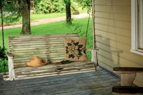 a porch swing with a cowboy hat and a hat at Charming and Intimate Suite Rental with a Soaking Tub near Houston, Texas in Cat Spring