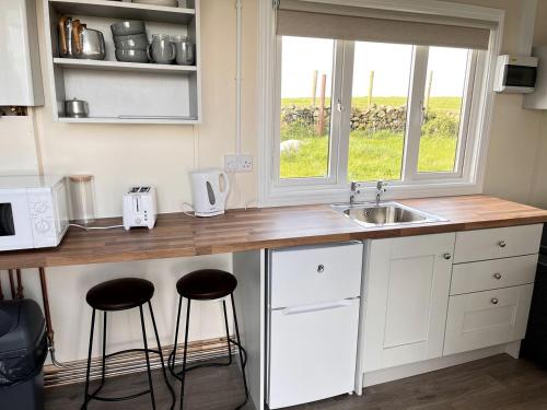 a kitchen with a counter with stools and a sink at Fantastic Off-Grid Tiny House Fully Equipped with Beautiful Countryside Views in Ireland in Eighter