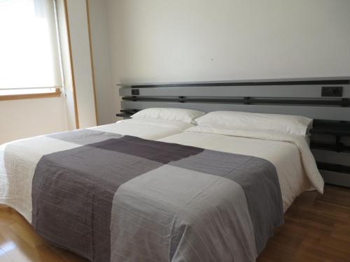 
a bed with a white comforter and pillows at Toctoc Rooms in A Coruña
