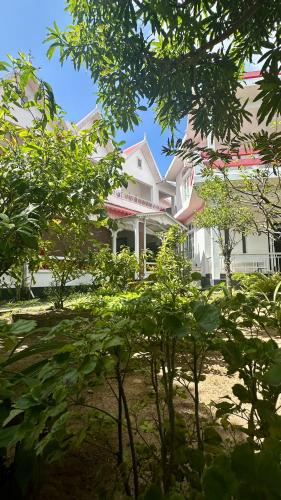 a large white house with trees in front of it at Pension Ciel d'Eté in Port Mathurin