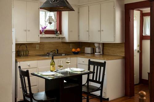 a kitchen with white cabinets and a table with two glasses of wine at Secluded Cabin Rental with Jacuzzi for Romantic Weekend Getaway near Austin, Texas in Cat Spring