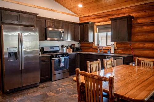 a kitchen with a table and a stainless steel refrigerator at Spacious Pet-Friendly Log Cabin with King Bed & Full Kitchen | Bonners Ferry, Idaho Retreat in Bonners Ferry