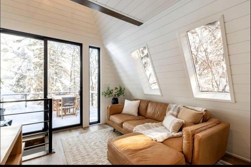a living room with a couch and windows at Lovely Secluded A-frame with Hot-tub in Sundance, Utah in Sundance