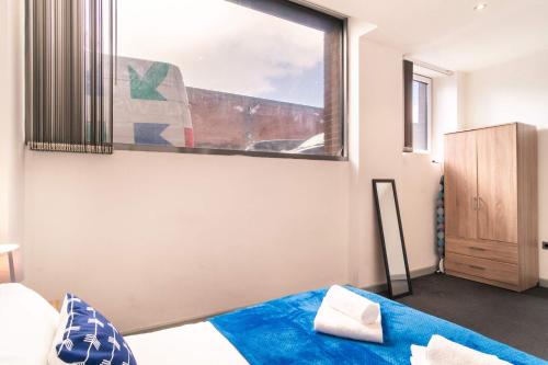 a bedroom with a window and a bed with blue sheets at Fabulous Central Blackburn 1 Bed Apartment in Blackburn