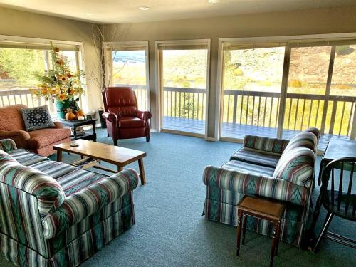 un salon avec des canapés, des chaises et des fenêtres dans l'établissement Spacious Vacation Home with Madison River Frontage near Yellowstone in Ennis, Montana, à Cliff Lake