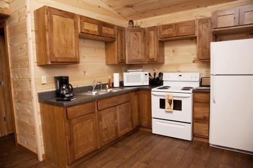a kitchen with wooden cabinets and a white refrigerator at Fantastic Cozy Cabin with Fire Pit, Hot-tub and Fireplace in Herod, Illinois in Karbers Ridge