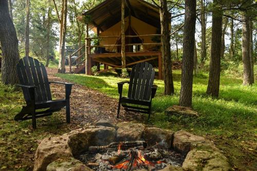 two chairs sitting around a fire in front of a cabin at Luxury Safari Style Tents for Getaways in Pennsylvania in East Berlin