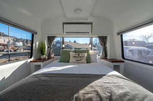 a bedroom with a bed and two windows at Downtown Prescott AZ Airstream Stay Near Whiskey Row with Outdoor Amenities in Prescott