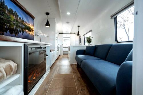 a living room with a blue couch and a fireplace at Downtown Prescott AZ Airstream Stay Near Whiskey Row with Outdoor Amenities in Prescott