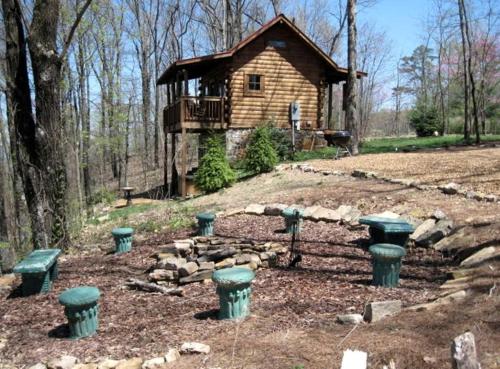 a group of green picnic tables in front of a log cabin at Log Cabin in the Clouds with Spectacular Views in Northern Chattanooga, Tennessee in Whitwell