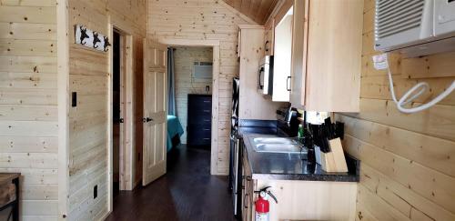 a kitchen with wooden walls and a sink in a tiny house at Texas State Glamping in this Charming Cabin Rental for Six in Pipe Creek in Pipe Creek