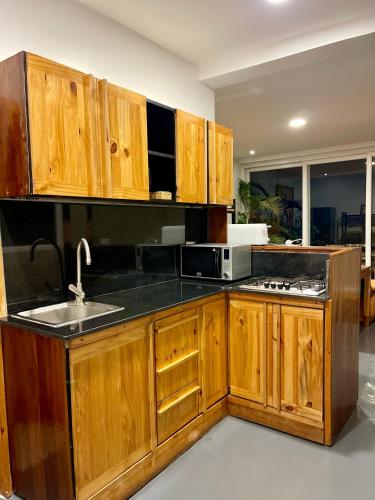a kitchen with wooden cabinets and a sink and a microwave at Eagle View Lodge - Kigali in Kigali