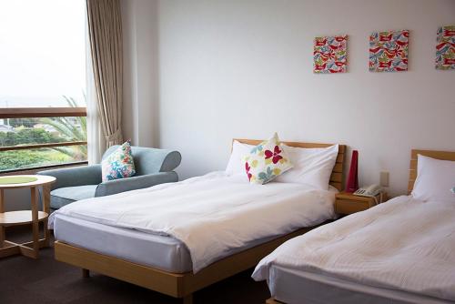a bedroom with two beds and a chair and a window at DokiDoggie館山DIANA in Tateyama