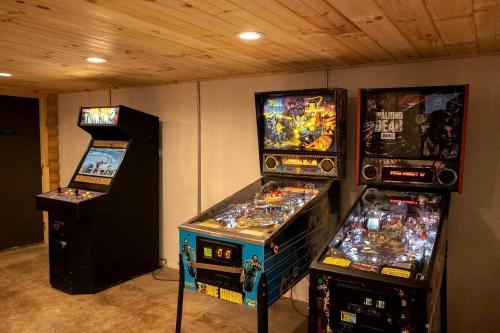 tre macchine per videogiochi sono allineate in una stanza di Rustic Tree A-Frame with Original Design by Tappan Lake in Ohio 