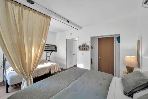 a white bedroom with a bed and a curtain at Upcycled Shipping Containers Transformed into a Glamping Home for a Unique Florida Vacation in Tequesta