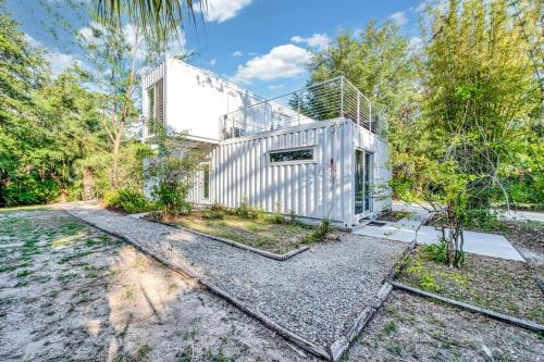 an exterior view of a white house in the woods at Upcycled Shipping Containers Transformed into a Glamping Home for a Unique Florida Vacation in Tequesta