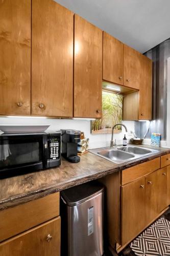 a kitchen with wooden cabinets and a sink and a microwave at Upcycled Shipping Containers Transformed into a Glamping Home for a Unique Florida Vacation in Tequesta