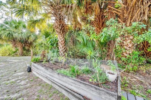 a wooden bench in front of a garden with palm trees at Upcycled Shipping Containers Transformed into a Glamping Home for a Unique Florida Vacation in Tequesta