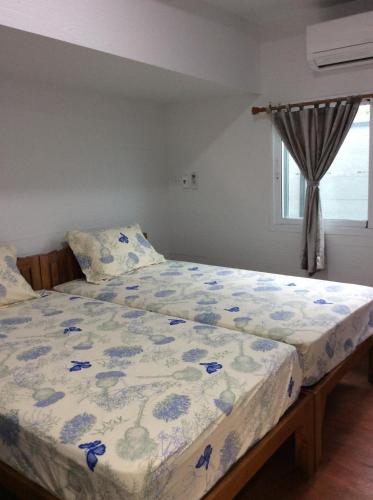 a bedroom with a bed with a floral bedspread at Sorn Waree Home place in Kanchanaburi City