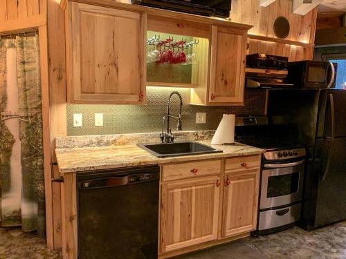 a kitchen with wooden cabinets and a sink and a stove at Unique Hobbit House Accommodation with a Private Hot Tub in Shenandoah, Virginia in Grove Hill