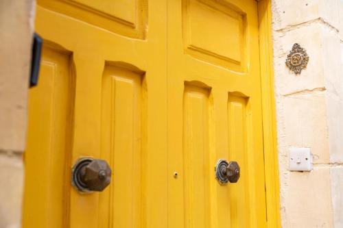 a yellow door with two handles on a building at Stay by the Grand Harbour of Valletta in Senglea
