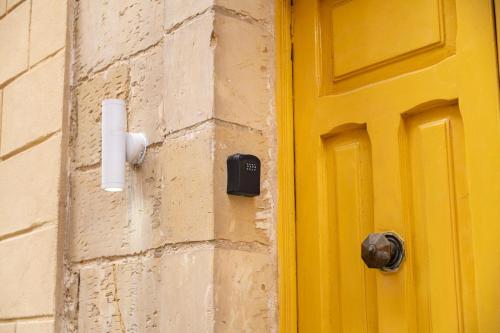 a yellow door on the side of a building at Stay by the Grand Harbour of Valletta in Senglea