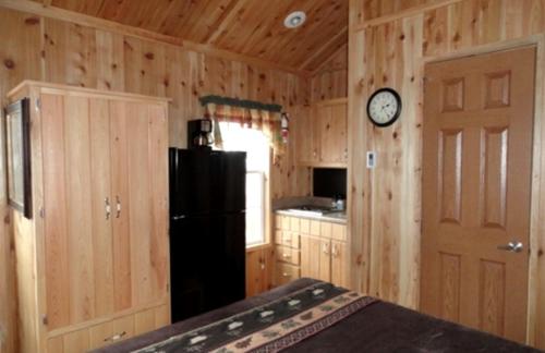 a kitchen with a black refrigerator and a clock on the wall at Family-Friendly Cabin Surrounded by Small Town Charm in Sundance, Wyoming in Sundance