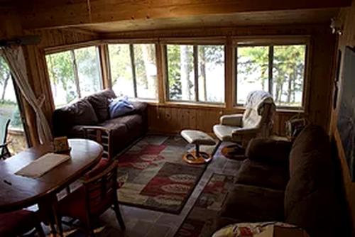 a living room with a couch and a table at Lakefront Cabin Rental with a Screened-In Porch near Pequot Lakes, Minnesota in Pine River