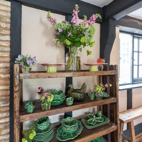 a shelf filled with green plates and vases with flowers at The Haven in Sandwich