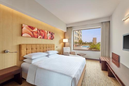 a hotel room with a bed and a large window at Four Points by Sheraton Hotel and Serviced Apartments Pune in Pune