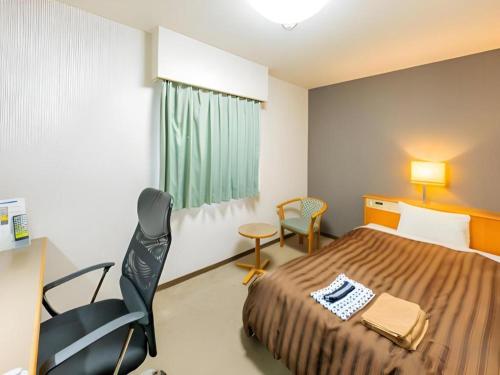 a bedroom with a bed and a desk and a chair at Mimatsu Hotel in Mito