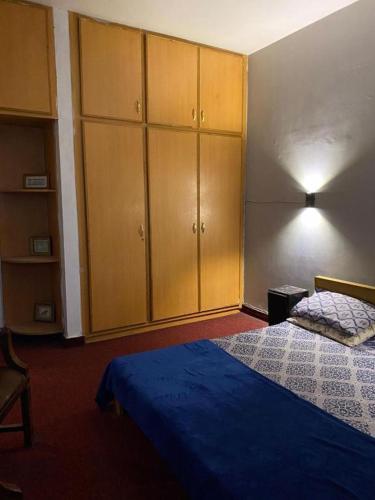 a bedroom with a bed and some wooden cabinets at Durrani House in Dargai