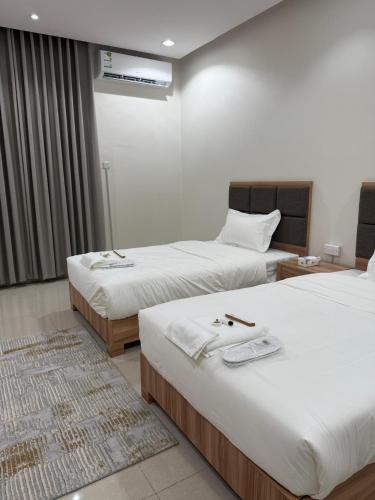 a hotel room with two beds with white sheets at شقق دفادف المخدومة in Hail