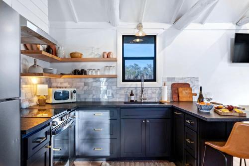 a kitchen with dark blue cabinets and a window at Pet-Friendly Glamping Cabin, with River Access in Ingram, Texas in Hunt