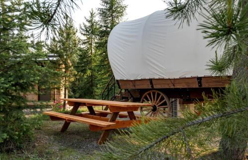 a picnic table and a white tent and a wagon at Charming Idaho Glamping Wagon with AC, Fire Pit & Breakfast | Bonners Ferry Escape in Bonners Ferry