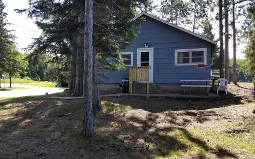 a blue tiny house in the middle of trees at Lakeside Cabin Rental with a Boat Launch near Tomahawk, Wisconsin in Tomahawk