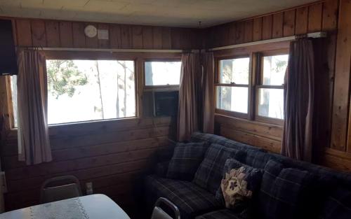 a living room with a couch and two windows at Lakeside Cabin Rental with a Boat Launch near Tomahawk, Wisconsin in Tomahawk