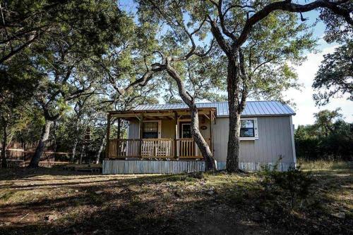 a small house with a porch in the woods at Rustic Dog-Friendly Cabin with Private Deck and Hot-Tub in Texas in Wimberley