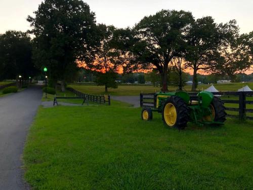 a tractor sitting on the grass in a field at Rustic Horse Stall Suite B&B Near Nashville and has Private Bath, Loft Beds & Country Breakfast in Cedar Grove