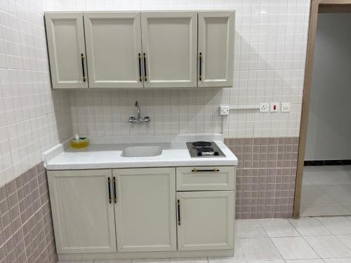 a kitchen with white cabinets and a sink at شقق دفادف المخدومة in Hail