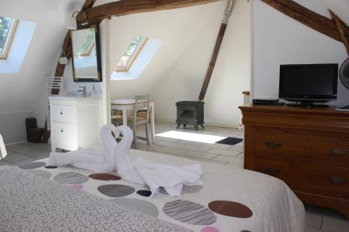 a bedroom with a bed with white sheets and a tv at Gîtes à l'ombre des chênes in Châteauvieux