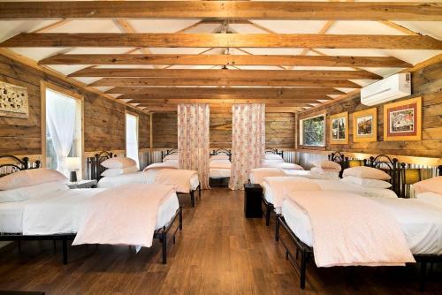 a row of beds in a room with wooden walls at Expansive Vacation Lodge Rental for 60 Guests in Covington, Louisiana in Covington