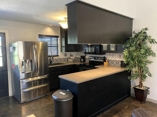 a kitchen with black cabinets and a stainless steel refrigerator at Wimberley Romance: Escape to a Cozy Cabin Nestled in Nature, TX in Woodcreek