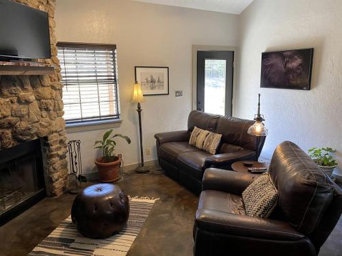 a living room with a leather couch and a fireplace at Wimberley Romance: Escape to a Cozy Cabin Nestled in Nature, TX in Woodcreek