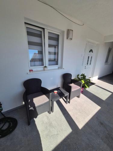 a room with two chairs and a table and windows at Airport Apartmani Nevena in Mitrovići