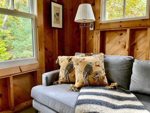 Una sala de estar con un sofá y dos ventanas. en Rustic Chic Maine Cabin @ Diagonair near Sedgwick, Maine, en Brooksville